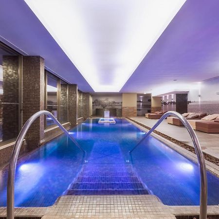 拉戈芒塔格别墅瑙酒店 蒙塔吉尔 外观 照片 The photo shows a modern indoor swimming pool area. The pool features a sleek design with steps leading into the water and a gentle curve at the sides. The water is illuminated in a blue hue, enhancing the relaxing atmosphere. Surrounding the pool ar