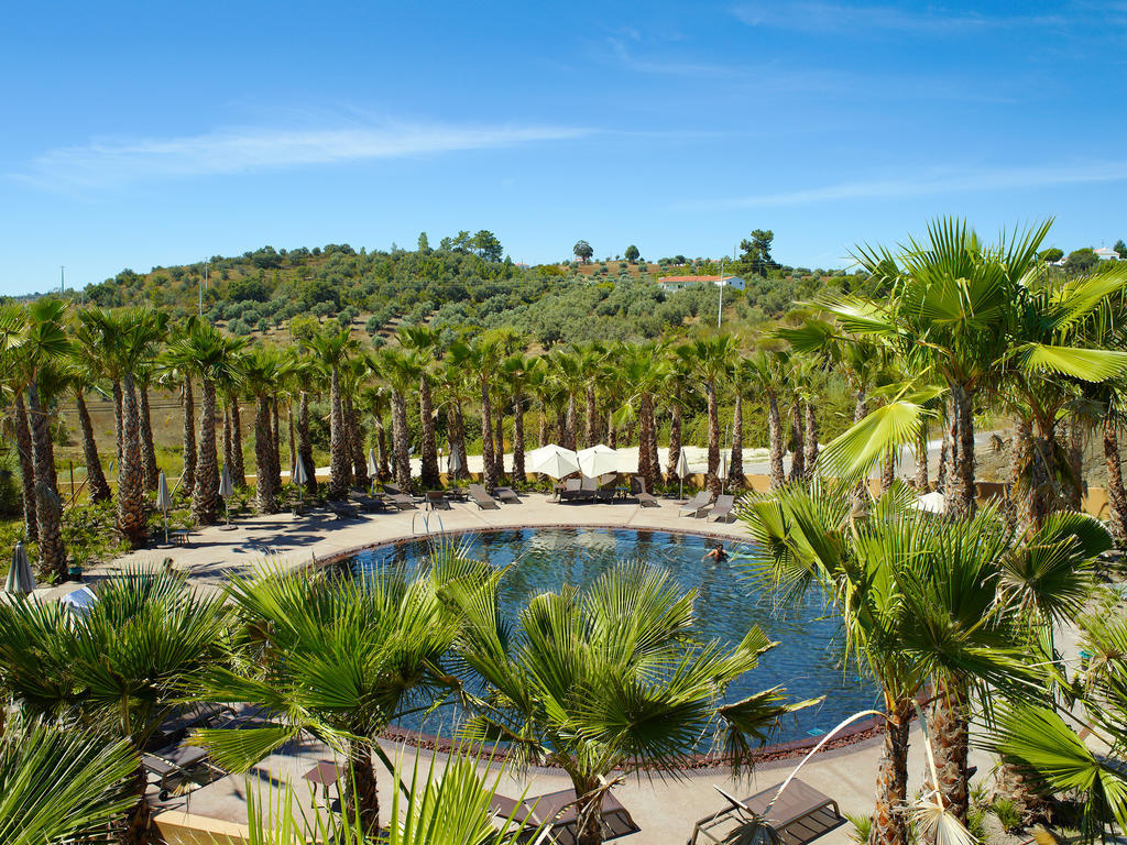 拉戈芒塔格别墅瑙酒店 蒙塔吉尔 外观 照片 The photo depicts a beautiful outdoor area featuring a circular swimming pool surrounded by palm trees. The pool area has several lounge chairs arranged around it. In the background, there is a lush green hillside, and the sky is clear with a bright 