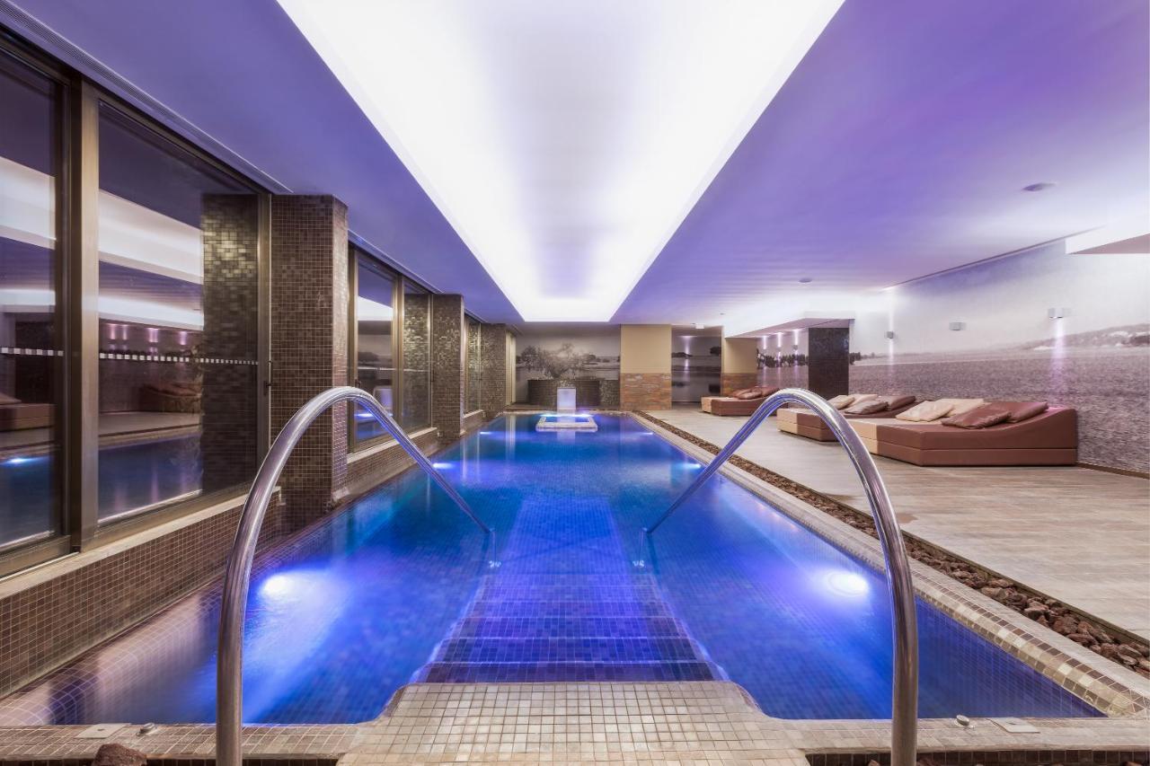 拉戈芒塔格别墅瑙酒店 蒙塔吉尔 外观 照片 The photo shows a modern indoor swimming pool area. The pool features a sleek design with steps leading into the water and a gentle curve at the sides. The water is illuminated in a blue hue, enhancing the relaxing atmosphere. Surrounding the pool ar