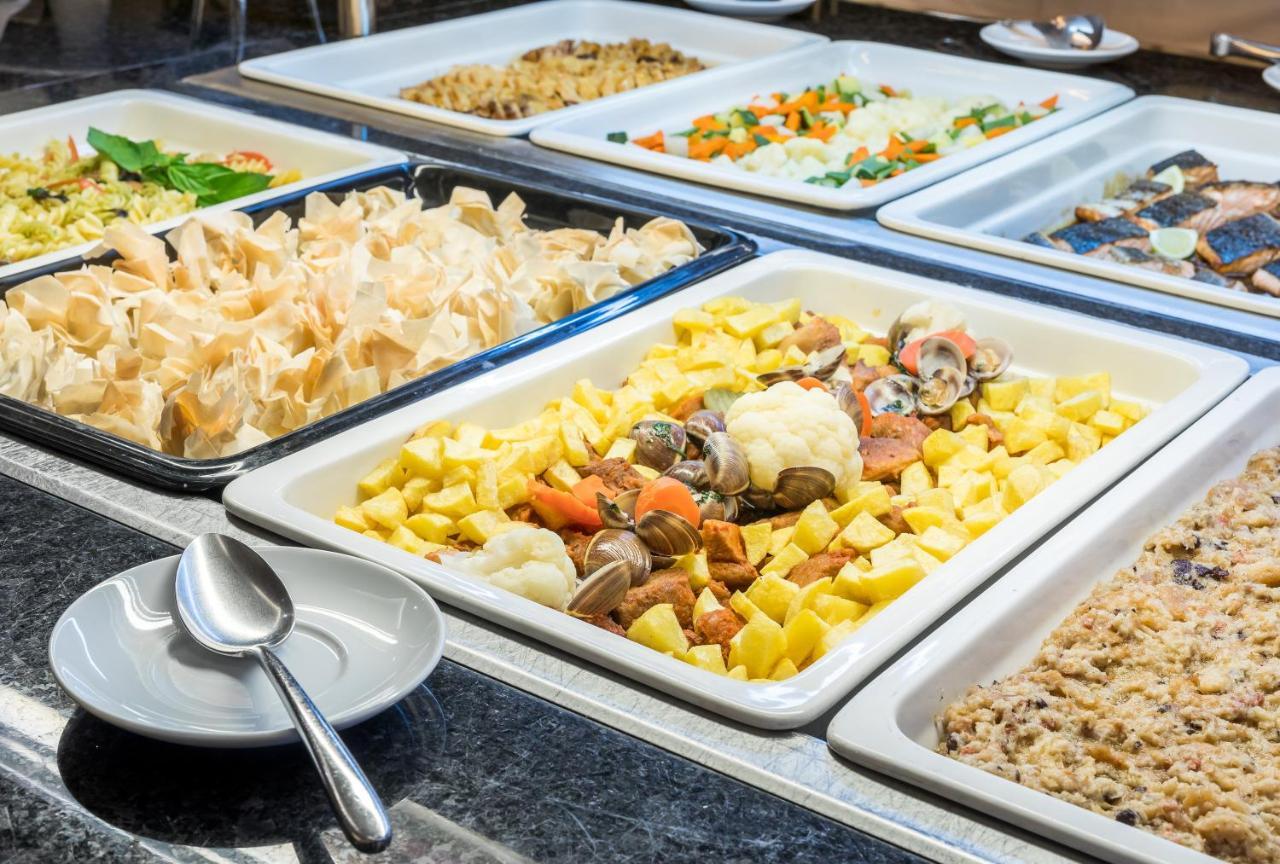 拉戈芒塔格别墅瑙酒店 蒙塔吉尔 外观 照片 The photo shows a buffet-style display of various dishes. There are several rectangular trays filled with different types of food. 

1. One tray contains a mix of vegetables and seafood, likely including potatoes and cauliflower.
2. Another tray hold