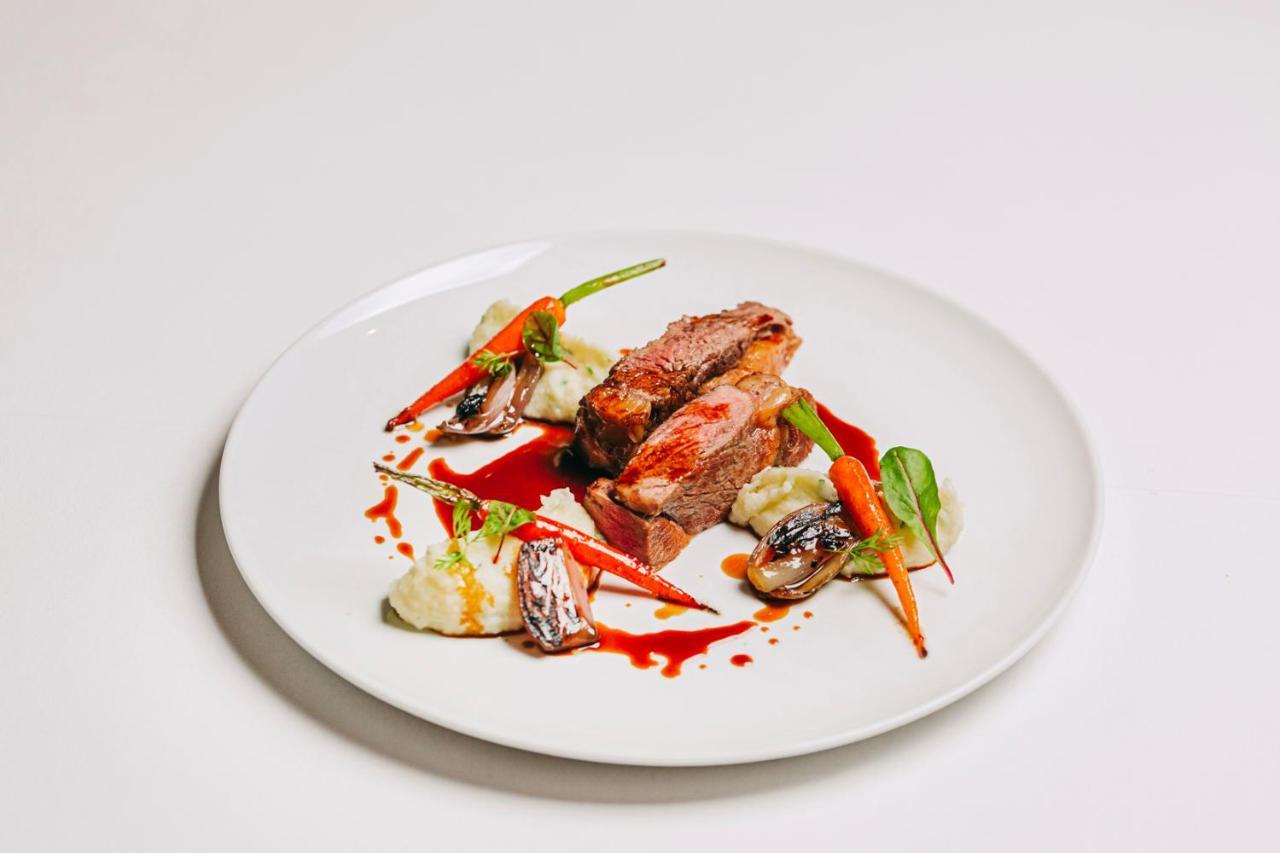 拉戈芒塔格别墅瑙酒店 蒙塔吉尔 外观 照片 The photo features a beautifully plated dish. At the center, there are slices of a tender meat, likely beef, showcasing a juicy pink interior. Accompanying the meat are several elements: vibrant orange carrots, perhaps roasted or glazed, and dollops 