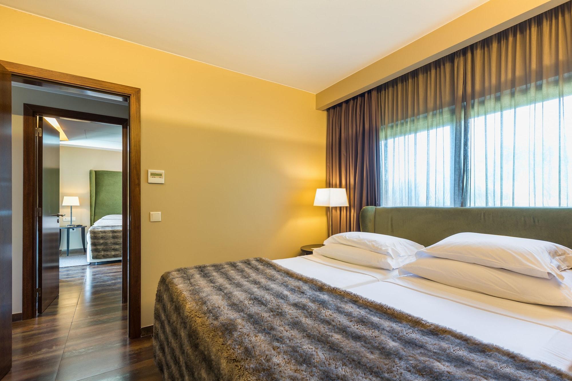 拉戈芒塔格别墅瑙酒店 蒙塔吉尔 外观 照片 The photo shows the interior of a well-furnished hotel room. It features two beds with white linens and a gray decorative throw on top. The walls are painted a warm yellow, and there are floor-to-ceiling windows covered with dark curtains that allow 