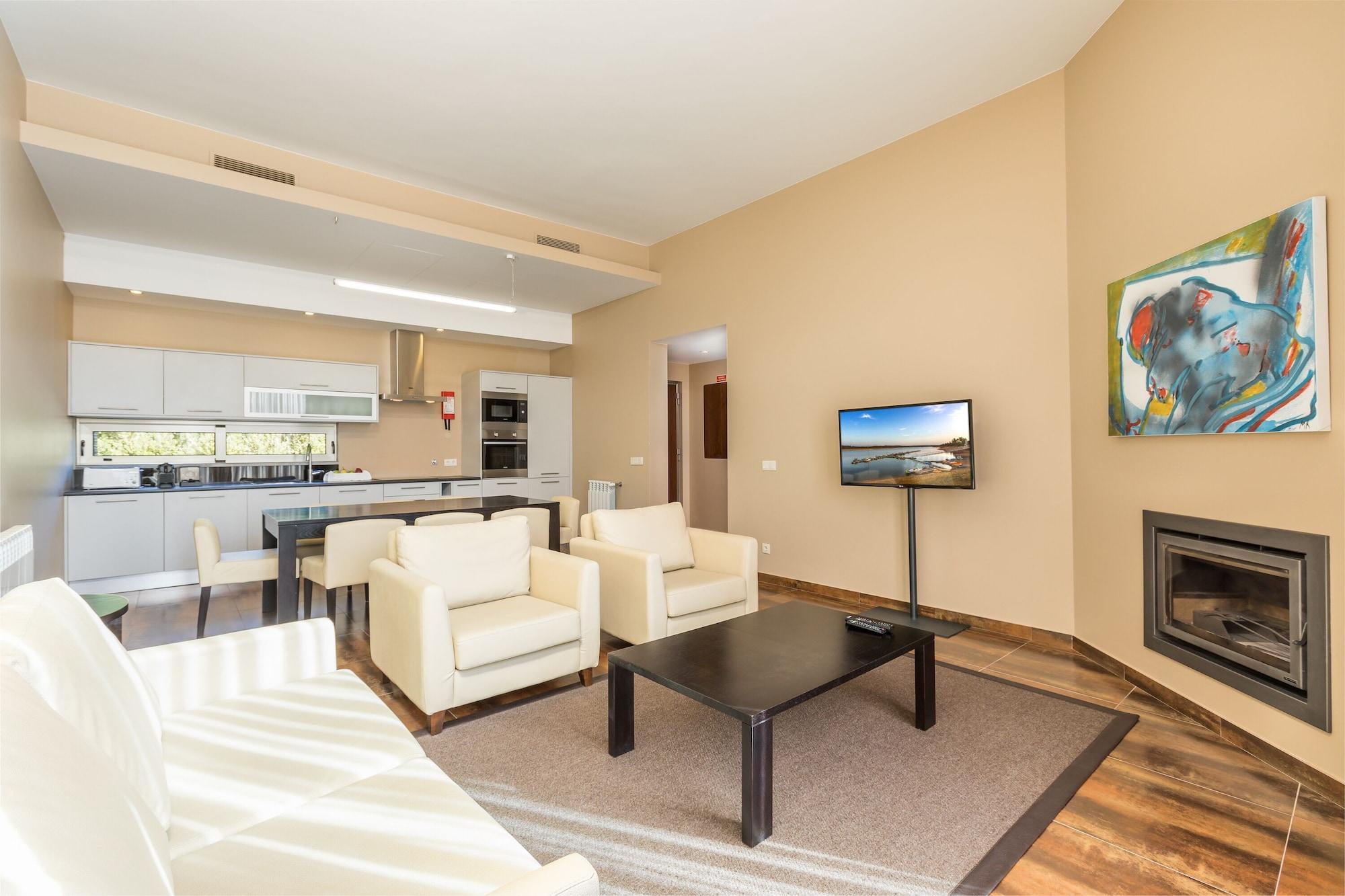 拉戈芒塔格别墅瑙酒店 蒙塔吉尔 外观 照片 The photo shows a modern, spacious living area with a contemporary design. The room features light-colored walls and wooden flooring. 

In the center, there is a black coffee table surrounded by four white armchairs. A flat-screen TV is mounted on th