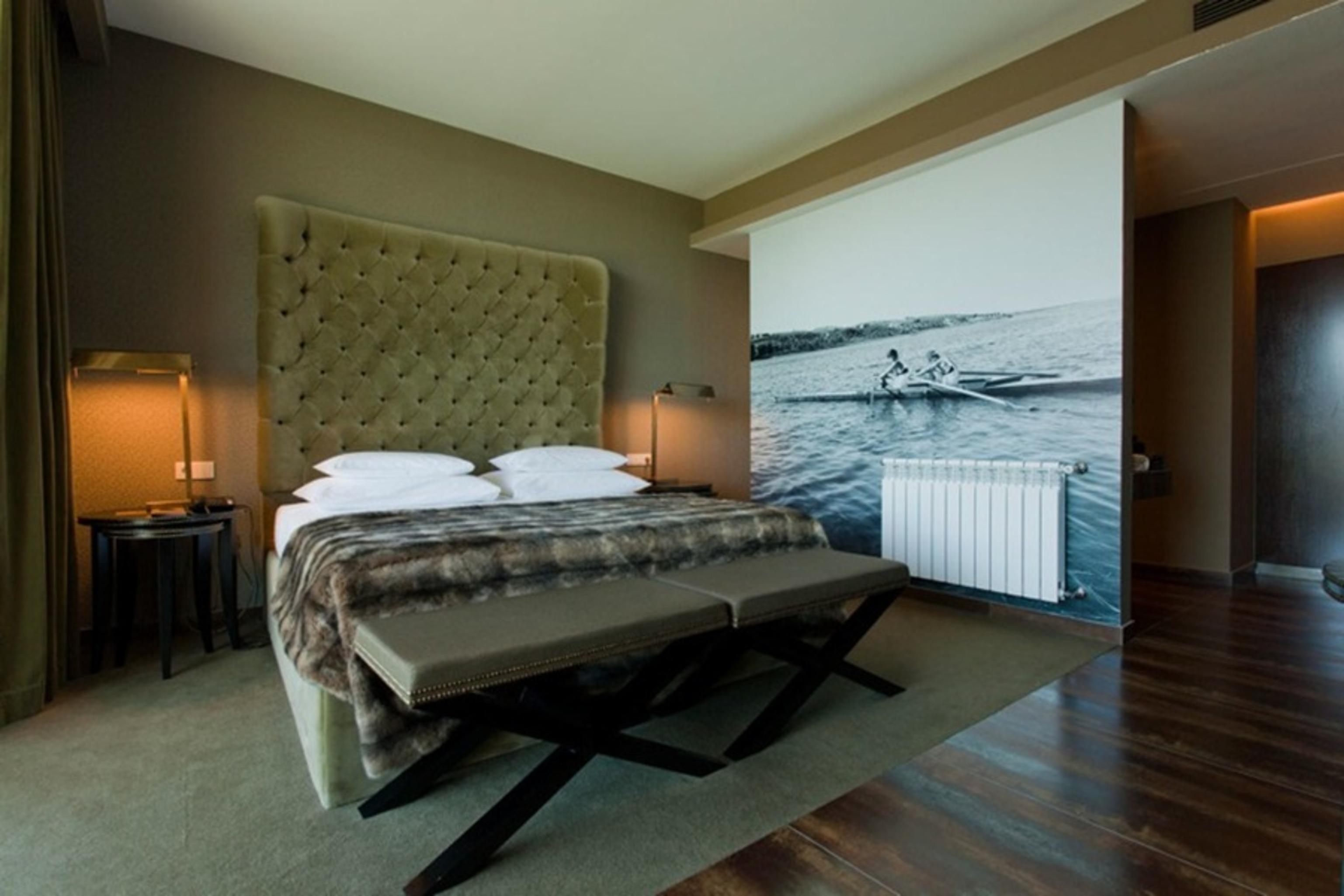 拉戈芒塔格别墅瑙酒店 蒙塔吉尔 外观 照片 The photo shows a modern hotel room featuring a large bed with a tufted headboard and plush bedding. The color palette is neutral, with shades of green and gray. On one side of the room, there are bedside tables with lamps. A comfortable bench sits a