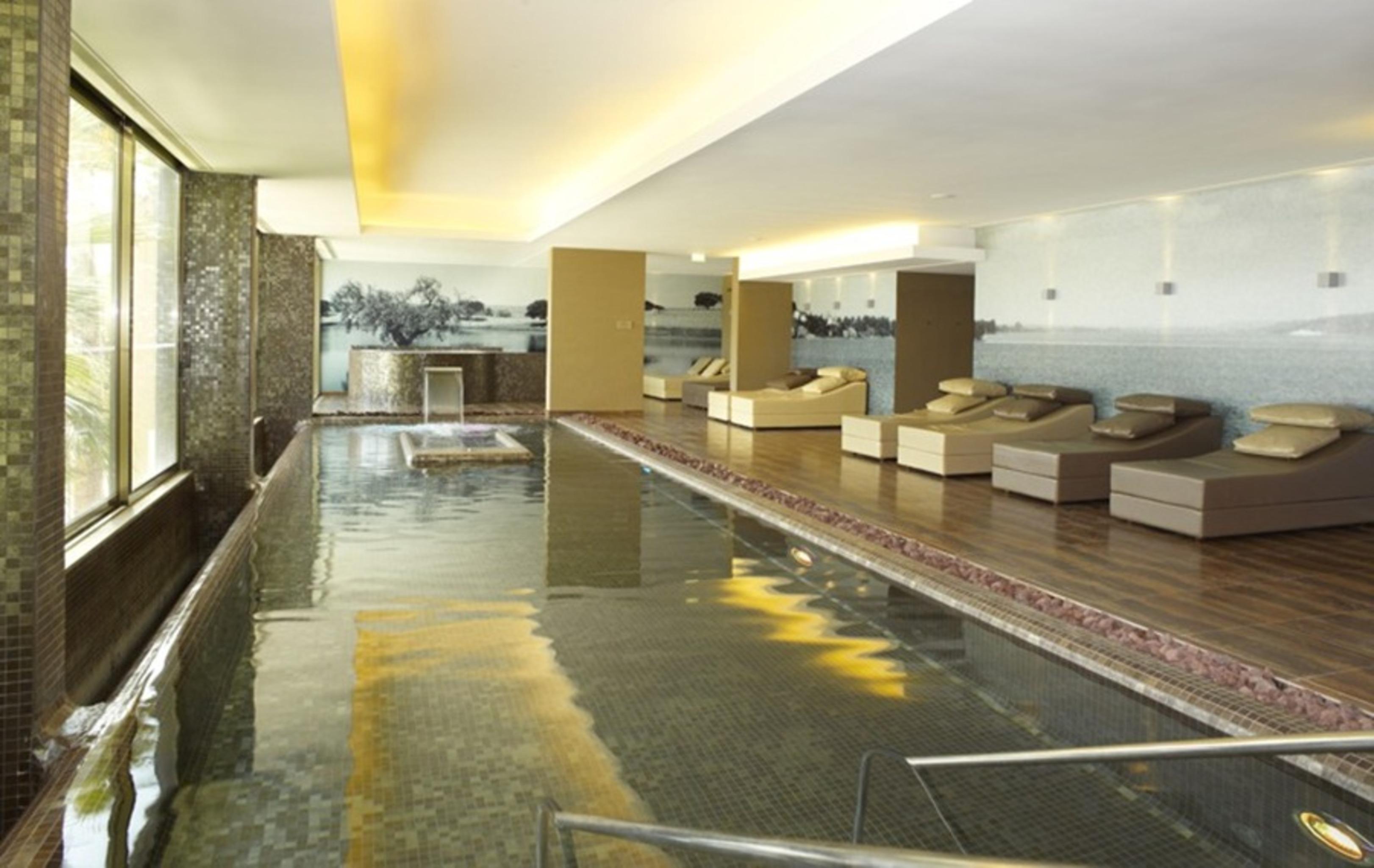 拉戈芒塔格别墅瑙酒店 蒙塔吉尔 外观 照片 The photo shows a modern, serene spa environment. There is a swimming pool with calm water, reflecting the surrounding decor. Along the sides, there are several comfortable lounge chairs arranged, perfect for relaxation. Large windows allow natural l