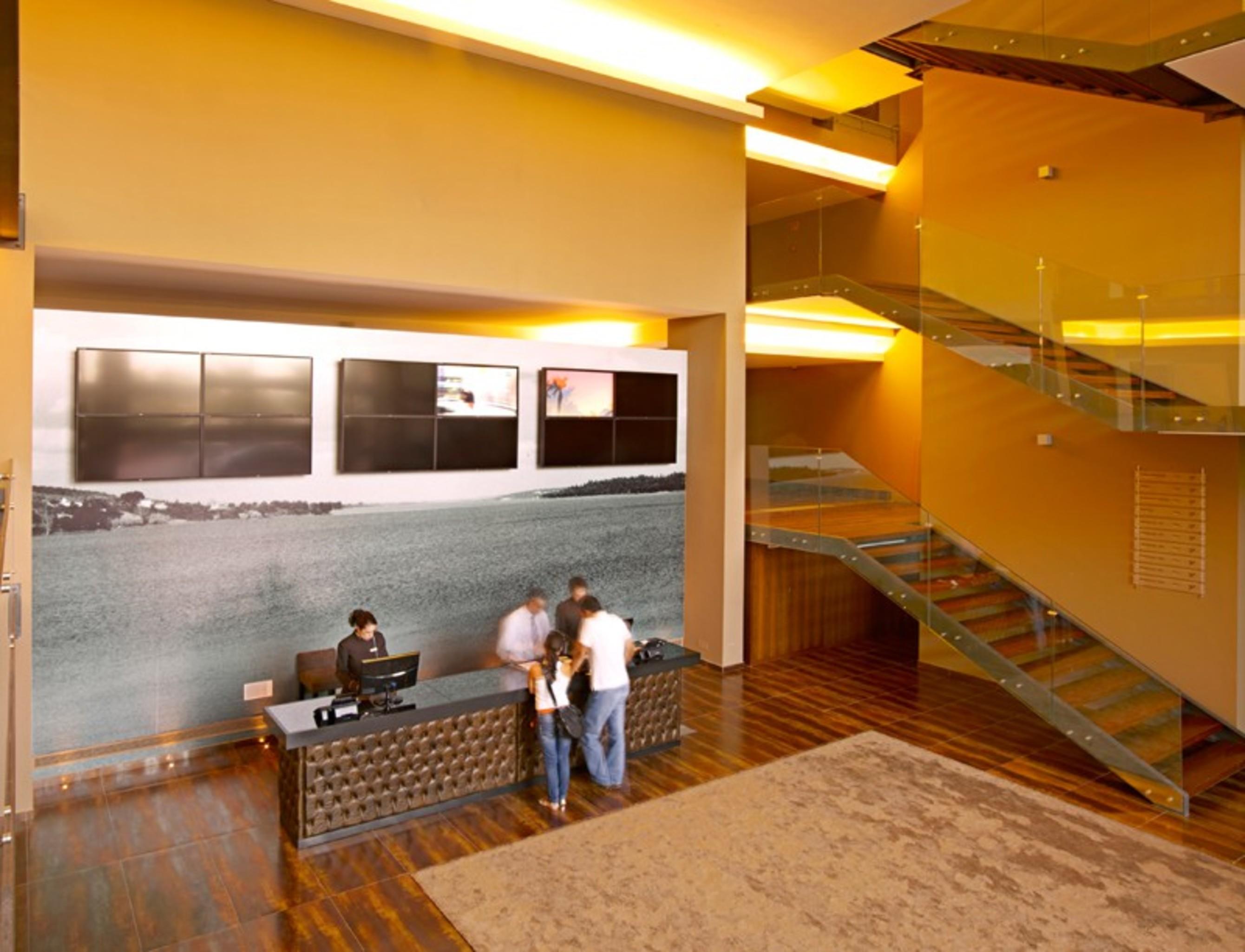 拉戈芒塔格别墅瑙酒店 蒙塔吉尔 外观 照片 The photo depicts a modern lobby area with a reception desk. The design features a combination of warm colors and wood flooring. In the background, there is a large wall-mounted screen or display, showcasing several monitors. The wall behind the desk