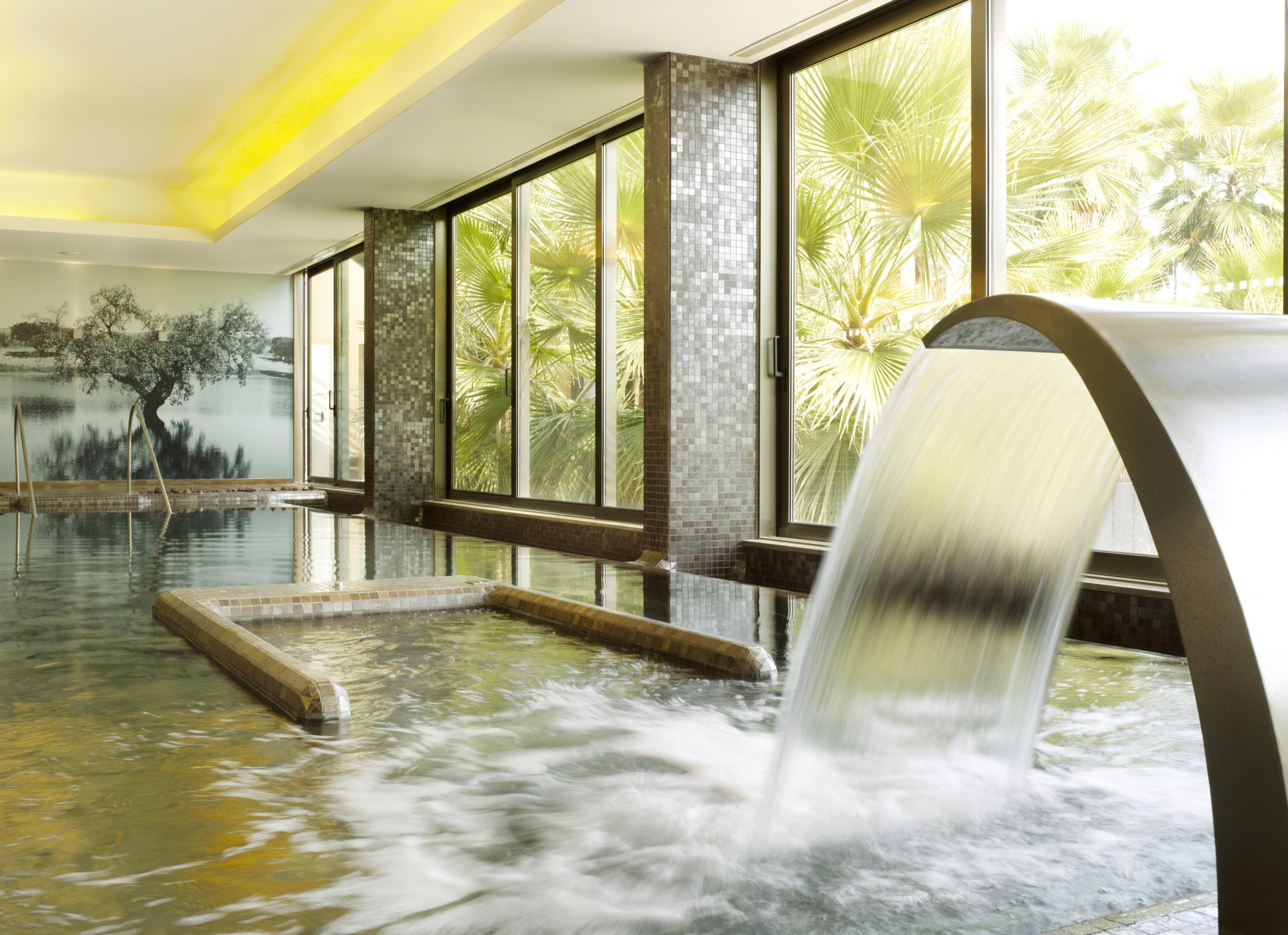 拉戈芒塔格别墅瑙酒店 蒙塔吉尔 外观 照片 The photo depicts a serene spa environment featuring a tranquil indoor pool area. There is a sleek, modern water feature that spills water gracefully into the pool. Large windows allow natural light to flood the space, showcasing views of lush greene