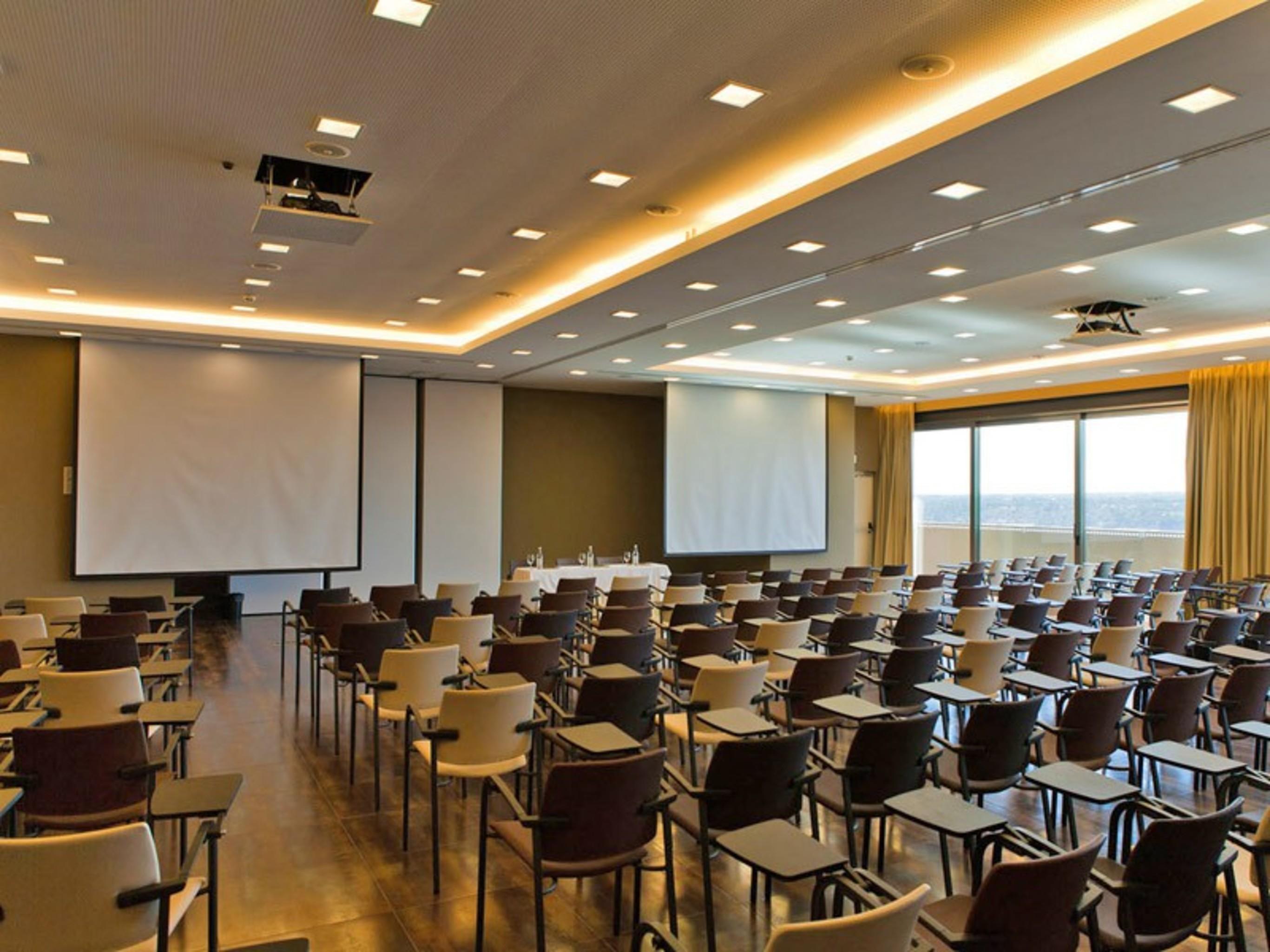 拉戈芒塔格别墅瑙酒店 蒙塔吉尔 外观 照片 The photo shows a large conference room set up for a presentation or meeting. There are multiple rows of chairs arranged in a semi-theater style, facing two large projection screens. The room has a modern design, with soft lighting and large windows 