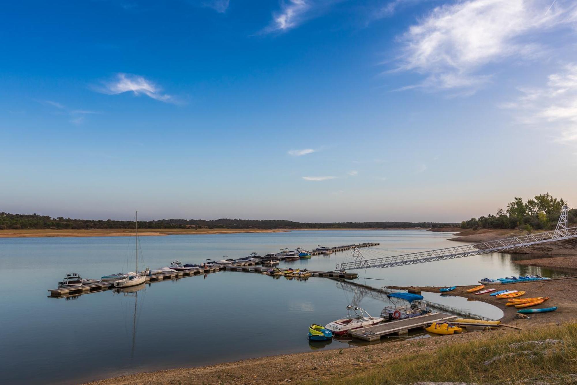 拉戈芒塔格别墅瑙酒店 蒙塔吉尔 外观 照片 The photo shows a serene lakeside scene. In the foreground, there are several boats moored at a dock, with some colorful kayaks and canoes lined up along the shore. The water is calm and reflects the sky, which features a few wispy clouds. In the bac